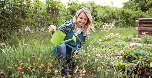 Woman smiling and watering her garden