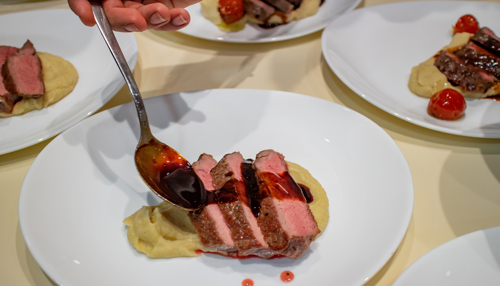 red wine reduction sauce drizzling on steak