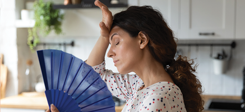 Woman using hand fan in kitchen